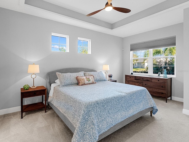 bedroom featuring ceiling fan, light carpet, and a tray ceiling