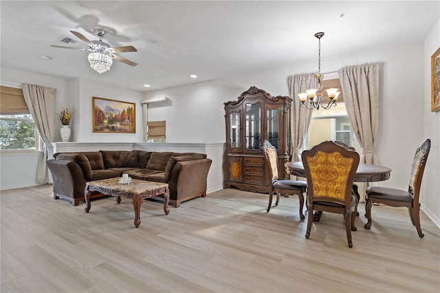 dining space featuring ceiling fan with notable chandelier and light wood-type flooring