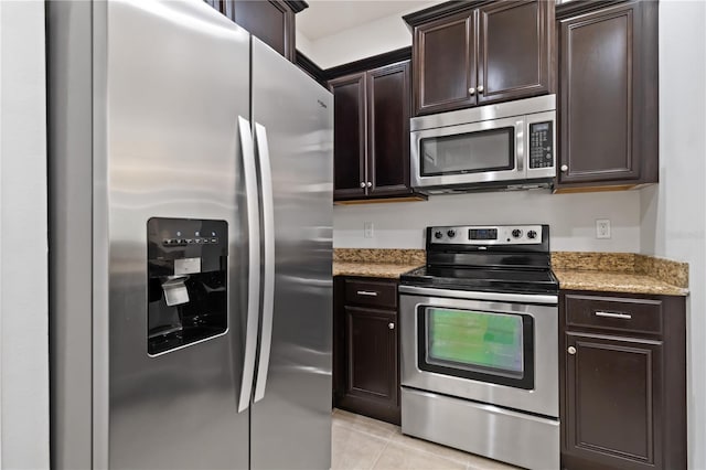 kitchen featuring light stone counters, dark brown cabinets, light tile patterned flooring, and stainless steel appliances