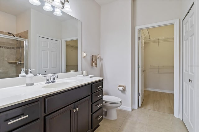 bathroom featuring tile patterned flooring, vanity, toilet, and walk in shower