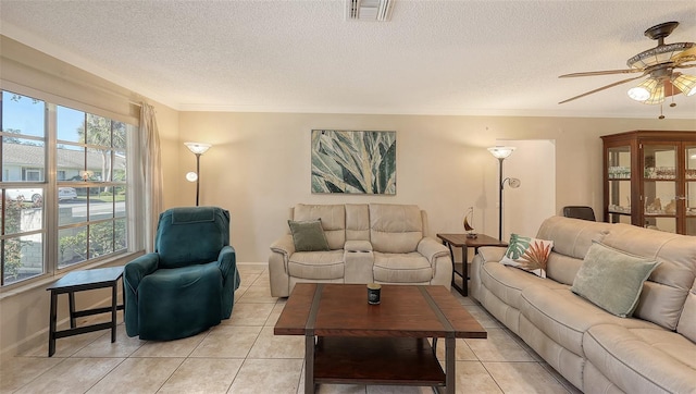 living room featuring a textured ceiling, ceiling fan, light tile patterned flooring, and crown molding