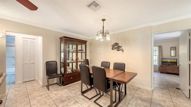 dining space with ceiling fan with notable chandelier, light tile patterned floors, a textured ceiling, and ornamental molding