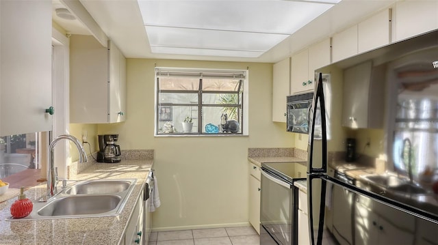 kitchen featuring stainless steel range, sink, light tile patterned floors, white cabinets, and fridge