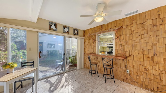 entryway featuring vaulted ceiling with beams, wooden walls, light tile patterned flooring, and ceiling fan