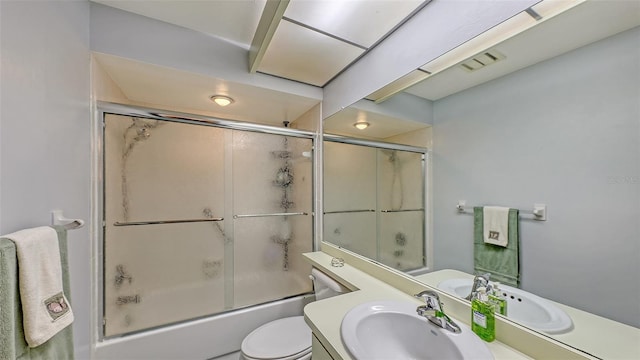 full bathroom featuring vanity, enclosed tub / shower combo, and toilet