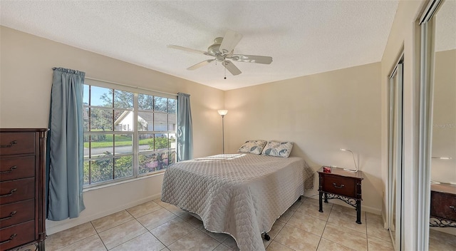 bedroom with ceiling fan, light tile patterned flooring, and a textured ceiling