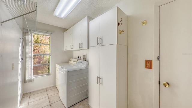 washroom featuring light tile patterned flooring, cabinets, a textured ceiling, and washing machine and clothes dryer