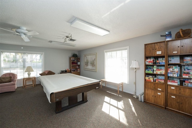 playroom with dark colored carpet, a textured ceiling, and a healthy amount of sunlight