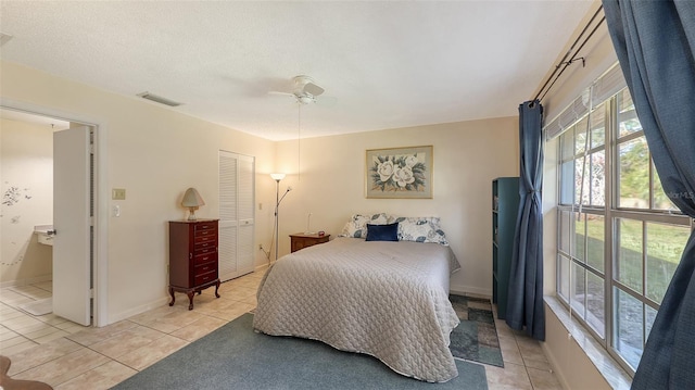 tiled bedroom featuring ceiling fan, a closet, and a textured ceiling