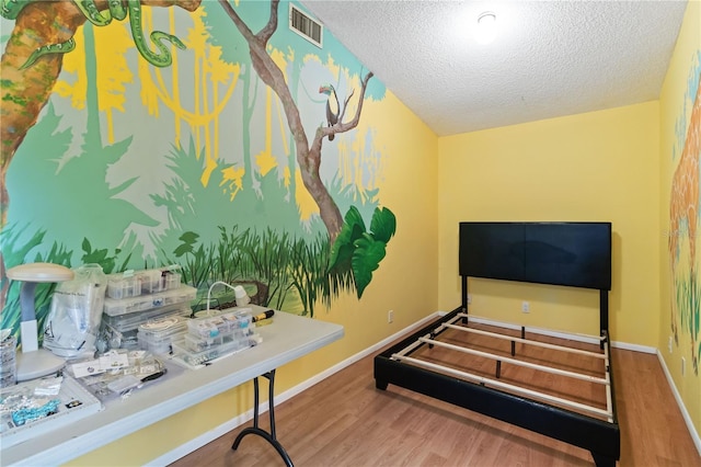 bedroom with wood-type flooring and a textured ceiling