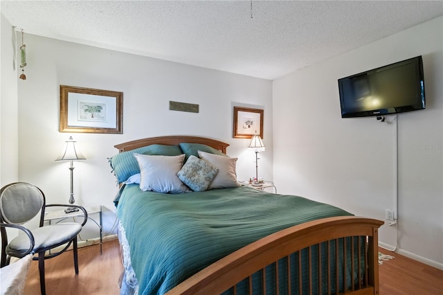 bedroom featuring light hardwood / wood-style floors and a textured ceiling