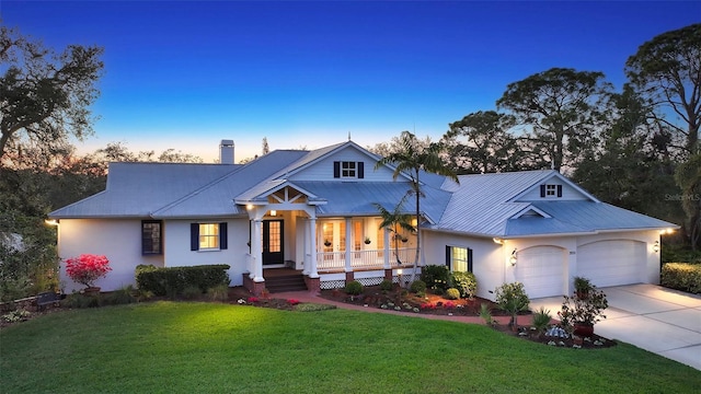 modern inspired farmhouse with concrete driveway, a chimney, metal roof, covered porch, and a front lawn