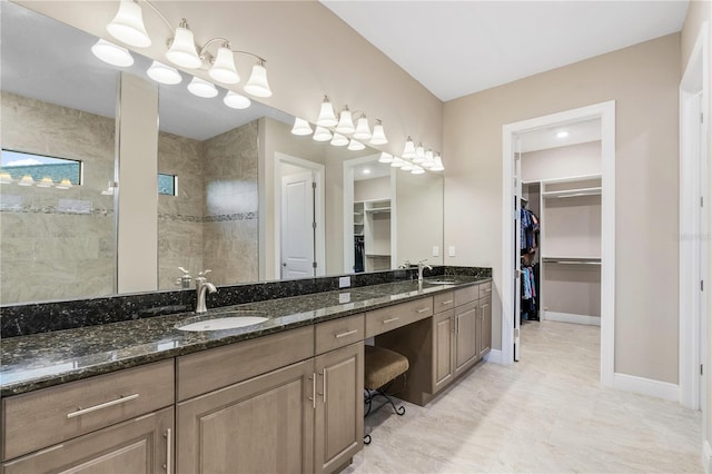 bathroom with a tile shower and vanity