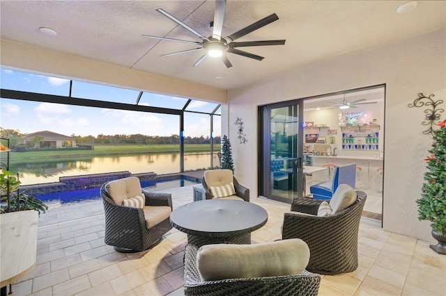 view of patio / terrace featuring a lanai, ceiling fan, and a water view