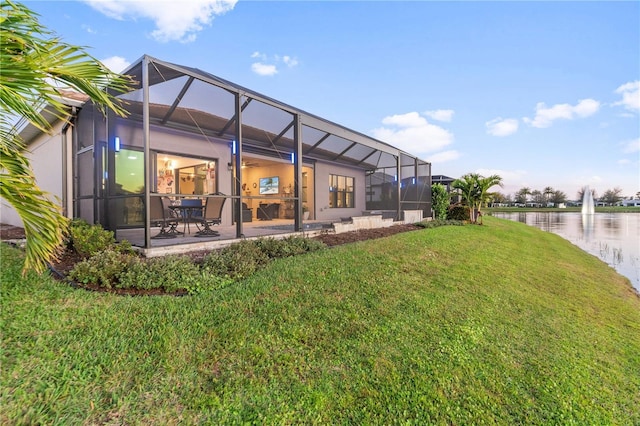 back of property with a water view, a yard, a lanai, and a patio area