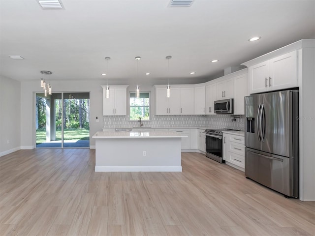 kitchen with white cabinetry, hanging light fixtures, stainless steel appliances, and light wood-type flooring