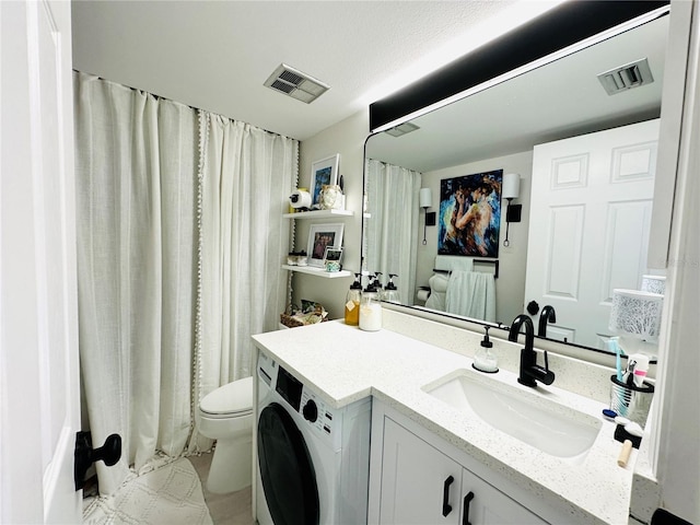 bathroom featuring toilet, vanity, and washer / dryer