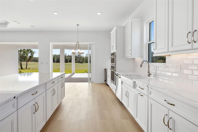 kitchen featuring white cabinetry, sink, light stone counters, and light wood-type flooring