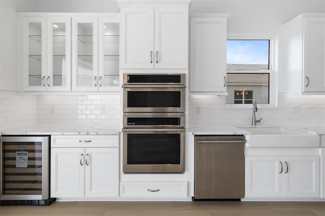 kitchen with white cabinetry, beverage cooler, light stone counters, and appliances with stainless steel finishes