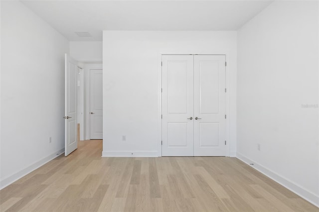 unfurnished bedroom with light wood-type flooring and a closet