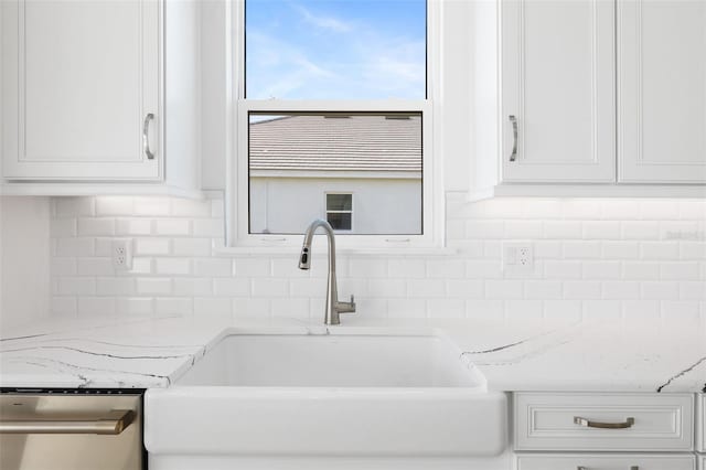 room details featuring light stone countertops, white cabinets, dishwasher, and sink