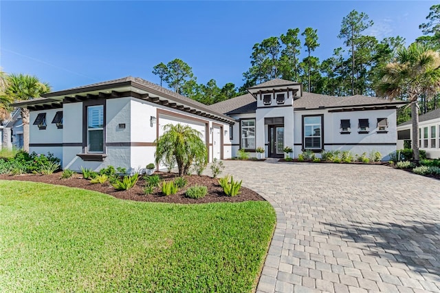 prairie-style home featuring a garage and a front lawn