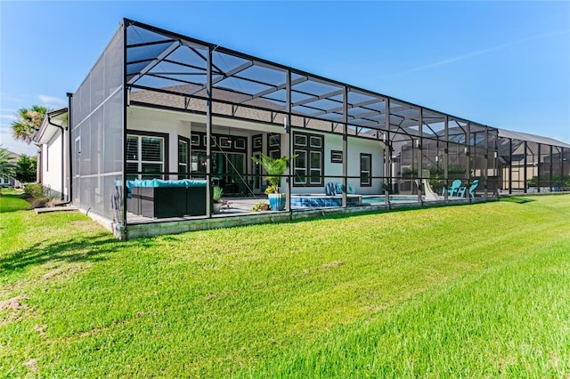 back of property with a yard, glass enclosure, and a patio area