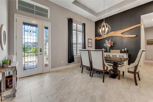 tiled dining room with a fireplace, a tray ceiling, and an inviting chandelier