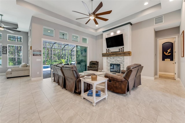 tiled living room featuring ceiling fan, a high ceiling, and a tray ceiling