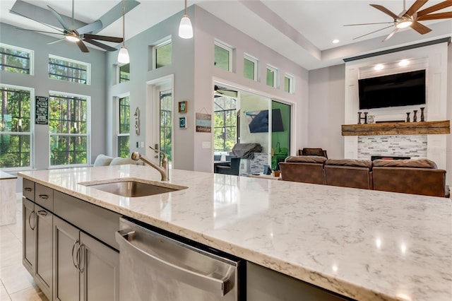 kitchen with dishwasher, light stone counters, plenty of natural light, and sink