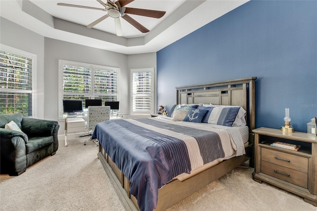 carpeted bedroom featuring a raised ceiling and ceiling fan