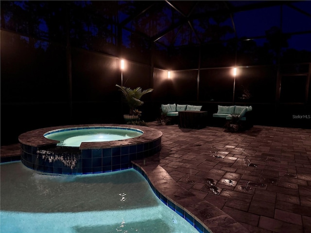 pool at night with a patio, an outdoor living space, an in ground hot tub, and glass enclosure