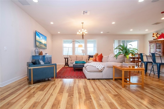 living room with plenty of natural light, light hardwood / wood-style floors, and an inviting chandelier