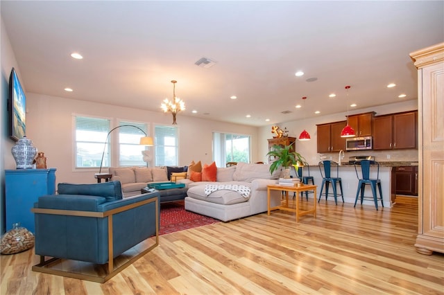 living room with light hardwood / wood-style floors, an inviting chandelier, and plenty of natural light