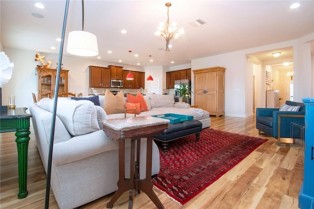 living room with an inviting chandelier and light wood-type flooring