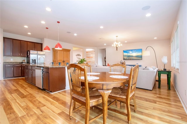 dining area featuring light hardwood / wood-style flooring, a chandelier, and sink