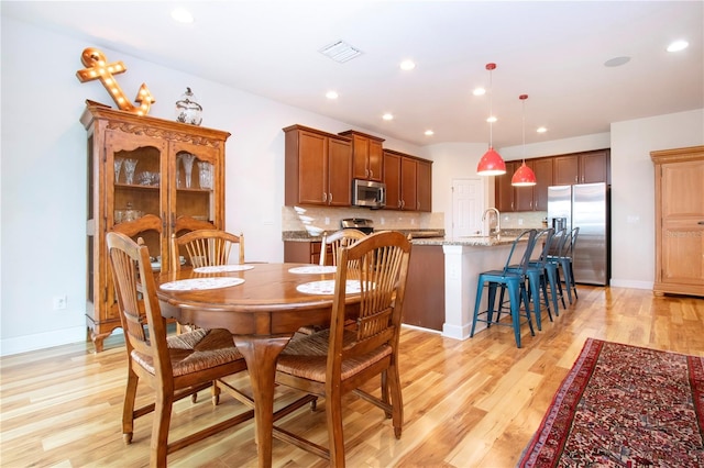 dining space with sink and light wood-type flooring