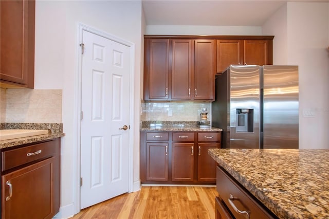 kitchen with decorative backsplash, stainless steel fridge, stone counters, and light hardwood / wood-style floors