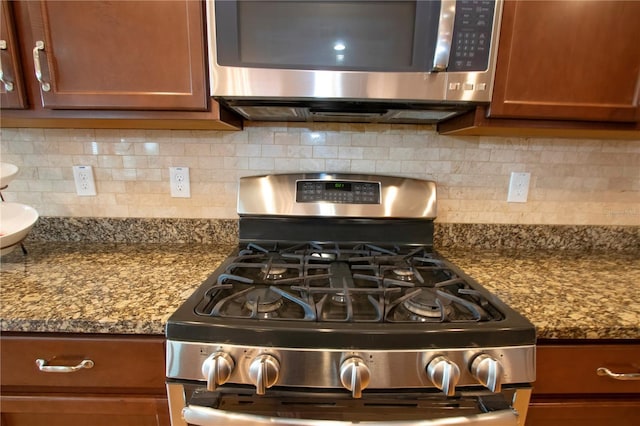 interior details with dark stone countertops, decorative backsplash, and appliances with stainless steel finishes