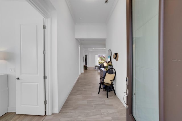 corridor with light hardwood / wood-style floors and crown molding