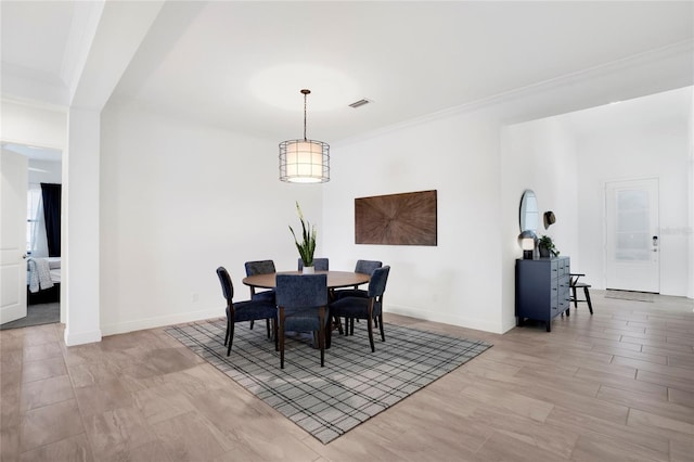 dining space with light hardwood / wood-style floors and crown molding