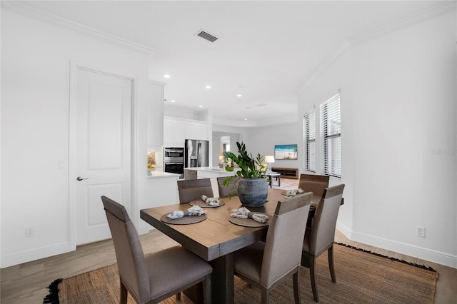 dining space with ornamental molding and light wood-type flooring