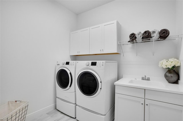 clothes washing area featuring cabinets, independent washer and dryer, light hardwood / wood-style floors, and sink