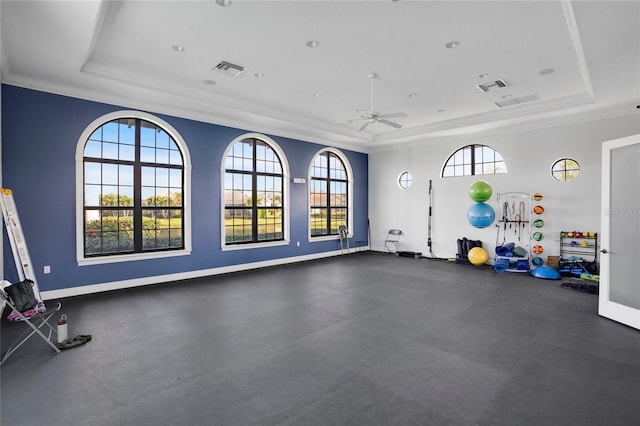 gym with a tray ceiling, ceiling fan, and ornamental molding