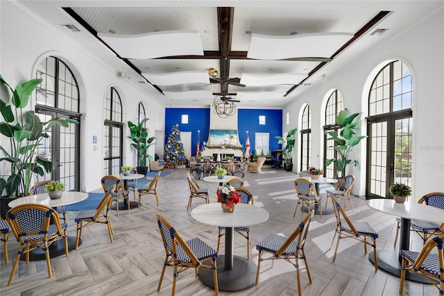 dining area with light parquet floors, a towering ceiling, and french doors