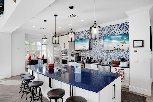 kitchen featuring white cabinetry, sink, stainless steel appliances, pendant lighting, and a spacious island