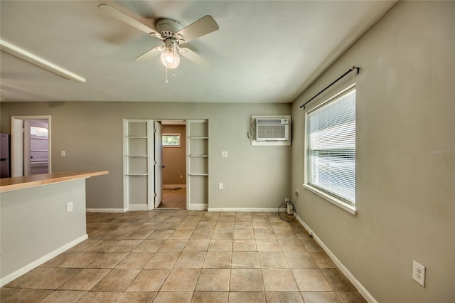 spare room featuring a wall mounted air conditioner, light tile patterned floors, and ceiling fan