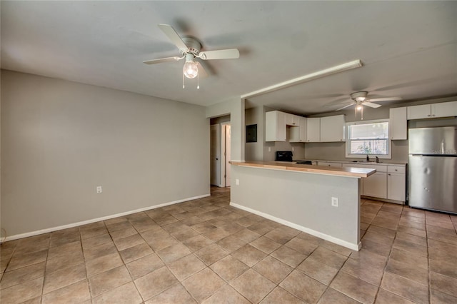 kitchen featuring white cabinets, black stove, sink, stainless steel fridge, and kitchen peninsula