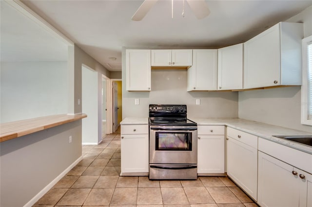 kitchen with ceiling fan, white cabinets, light tile patterned flooring, and stainless steel electric range