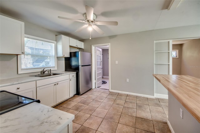 kitchen with stainless steel refrigerator, sink, and white cabinets